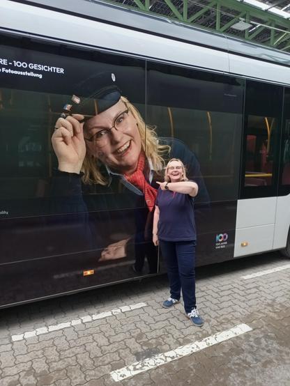 Frau Müller MeierSchulze als überdimensionales Bild auf der Seitenwand eines Busses und live daneben stehend