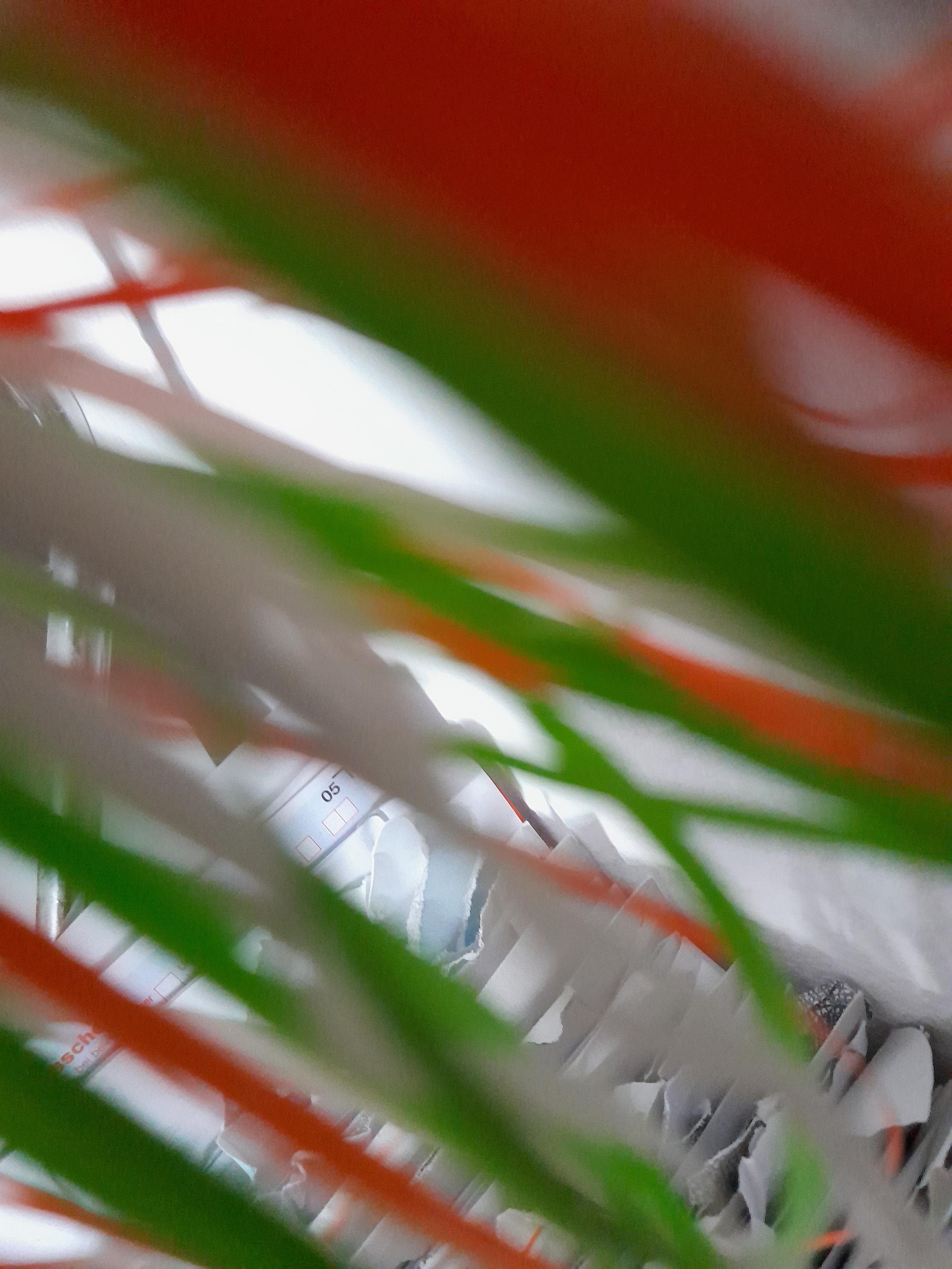 Verschwommene Aufnahme von schmalen Bändern in den Farben orange, grün und weiß.